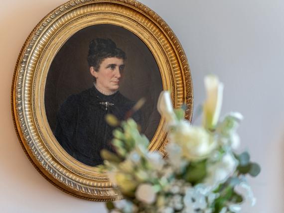 Portrait of a woman in an oval gold frame at Hotel Adria with flowers in foreground