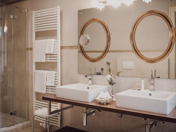 Hotel Adria bathroom with double sinks and two round mirrors