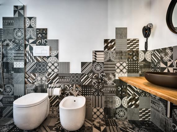 Bagno con piastrelle decorate, WC e lavabo al Teku Boutique Hotel