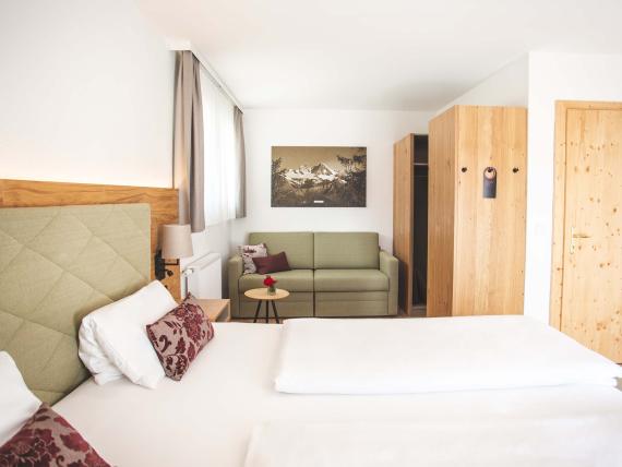 Der Dolomitenhof ***S bequemes Doppelzimmer mit Sofa und Holzmöbeln