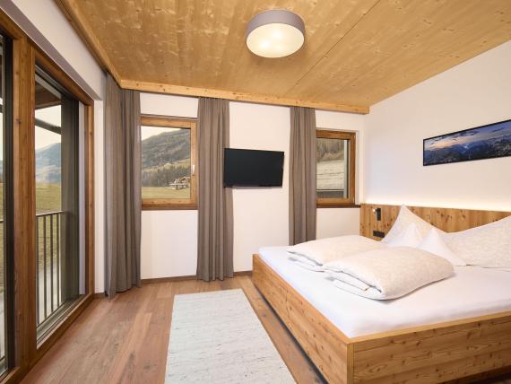 Schlafzimmer im Hochfeldhof mit Holzdecke und Bergblick durchs Fenster