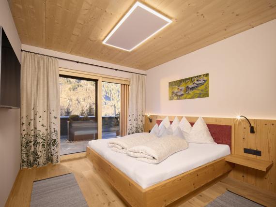 Gemütliches Schlafzimmer im Hochfeldhof mit Holzdecke und Balkonblick