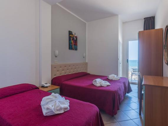 Camera d'hotel con due letti e fiori di asciugamani sulle coperte rosse