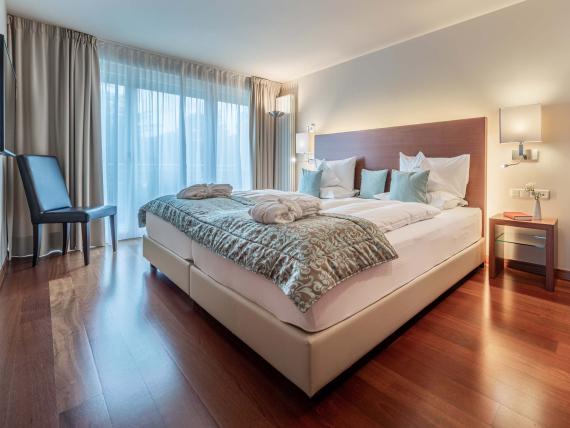 Modernes Schlafzimmer im Hotel Mignon Meran Park & Spa mit großem Bett und Holzfußboden