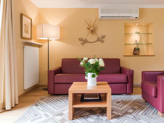 Gemütlicher Sitzbereich im Hotel Mignon Meran Park & Spa mit rotem Sofa und Vase