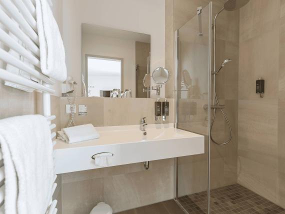 Modernes Badezimmer mit Dusche und Handtüchern im Mythenresort Heimdall