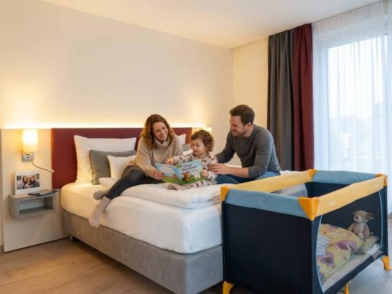 Familie liest auf dem Bett im Mythenresort Heimdall, Kinderreisebett nebenan