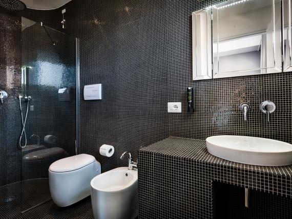 Bagno del Teku Boutique Hotel con mosaico nero, doccia, WC e lavabo