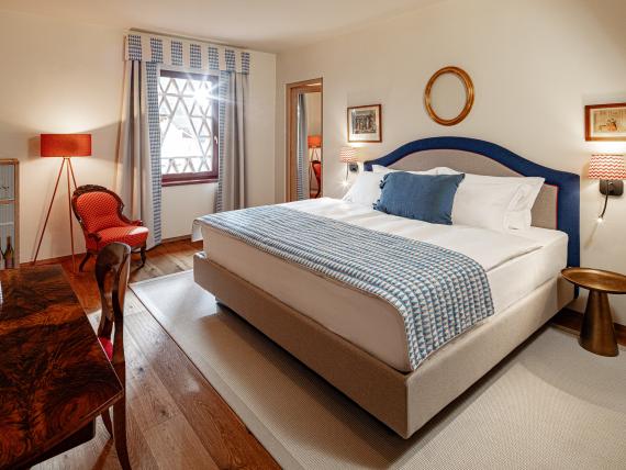 Gemütliches Schlafzimmer im Castel Sallegg mit Holzfußboden und rotem Sessel