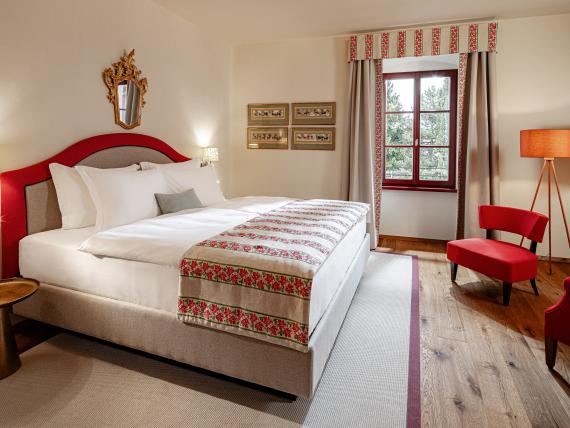 Gemütliches Schlafzimmer mit rotem Akzent und Fenster im Castel Sallegg