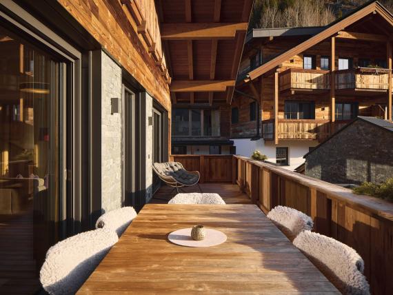 Balkon mit Holztisch und Stühlen am Hochfeldhof bei Sonnenlicht