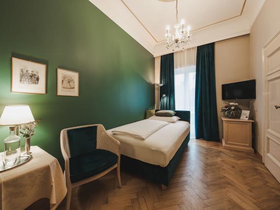 Single room at Hotel Adria with green accent wall and wooden floor