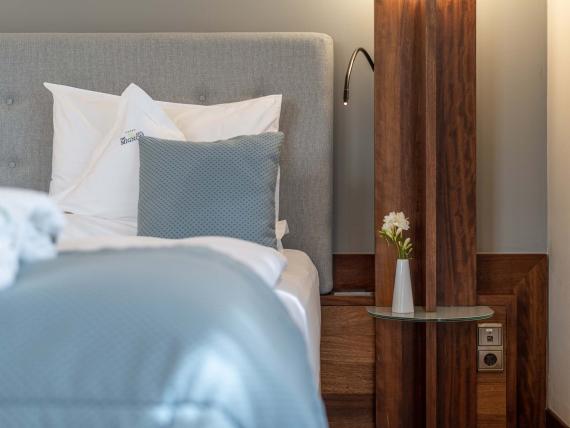 Hotel Mignon Meran Park & Spa gemütliches Bett mit grauem Kopfteil und Nachttisch