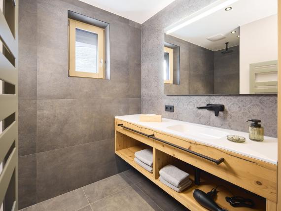Modernes Badezimmer im Hochfeldhof mit Holzwaschtisch und grauen Fliesen