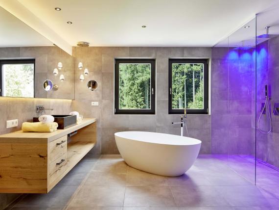 Moderne Badezimmereinrichtung im Naturhotel Die Waldruhe mit freistehender Badewanne und Blick ins Grüne