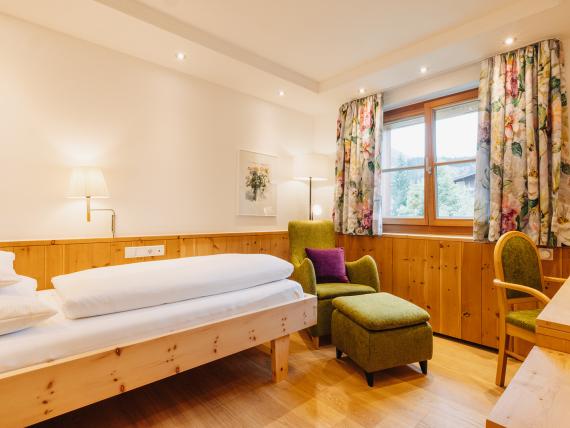 Gemütliches Zimmer im Hotel Aurora mit Holzdekor und einem grünen Sessel