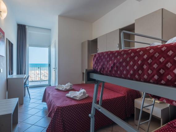 Camera d'hotel con coperte rosse a fiori e vista mare