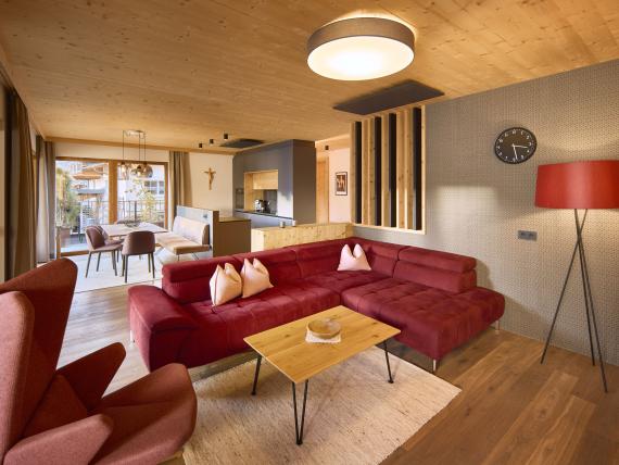 Gemütliches Wohnzimmer mit rotem Sofa und Holzdecke im Hochfeldhof