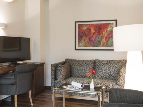Hotel Mignon Meran Park & Spa Zimmer mit Sofa, Fernseher und Tisch mit Blumen