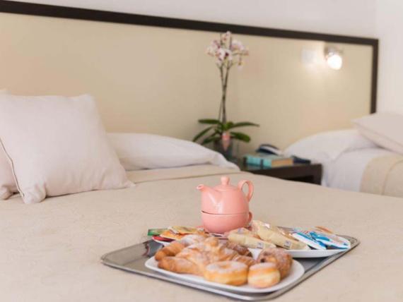 Vassoio con colazione e dolci sul letto nella camera dell'Hotel Viola Gaeta