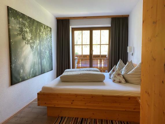 Gemütliches Schlafzimmer im Hochfeldhof mit Holzbettrahmen und Waldbild