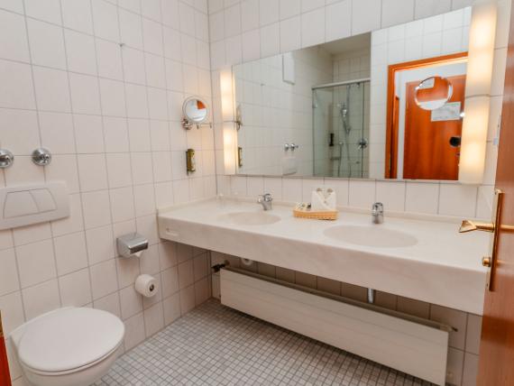 Badezimmer mit Doppelwaschbecken und Toilette im Parkhotel St. Leonhard Überlingen