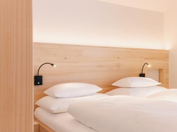 Schlafzimmer mit zwei Betten im Hotel Aurora mit Holzdekor und Leselampen