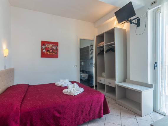 Camera da letto con copriletto rosso a fiori e armadio aperto