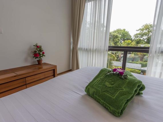 Cozy room at The Mangosteen Ayurveda & Wellness Resort with folded green towel and flowers