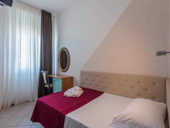 Camera da letto con fiori sul letto e luce naturale dalla finestra