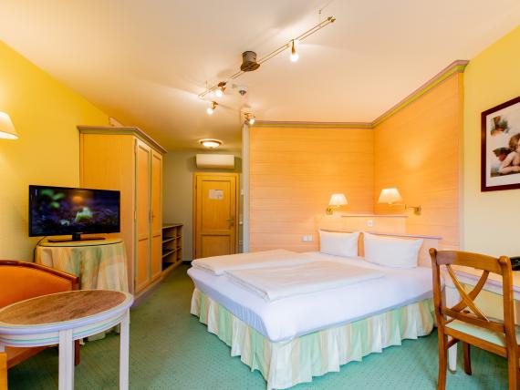 Gemütliches Zimmer im Pfalzblick Wald Spa Resort mit Doppelbett und TV
