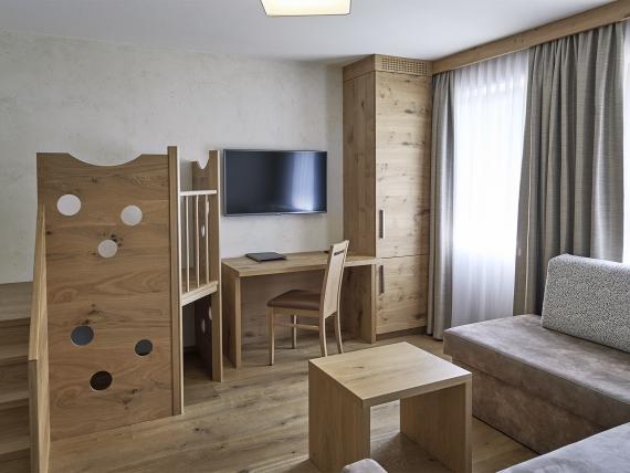 Modern room at Familienresort Buchau with wooden play area, TV, and sofa