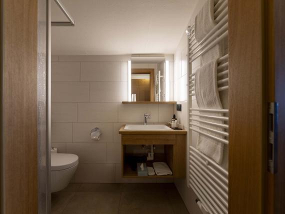 Bagno moderno al Das Unterrain Lifestyle Hotel con dettagli in legno e asciugamani