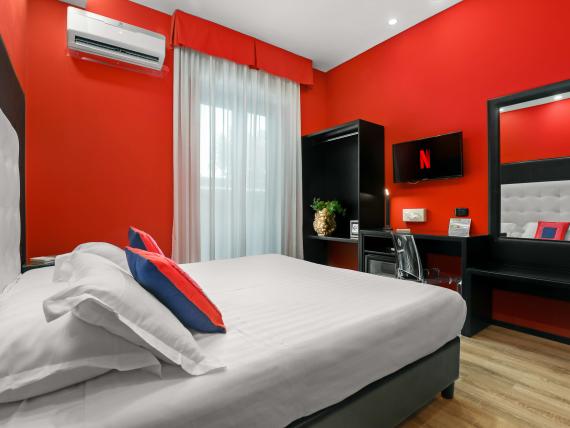 Camera moderna al Reggia Suite Spa Hotel con pareti rosse e letto bianco