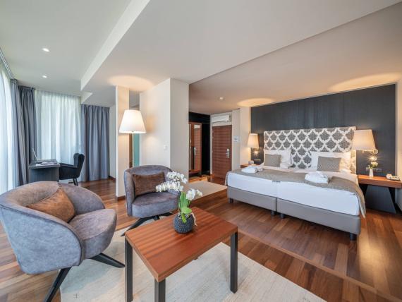 Modernes Zimmer im Hotel Mignon Meran Park & Spa mit Sitzbereich und Doppelbett.