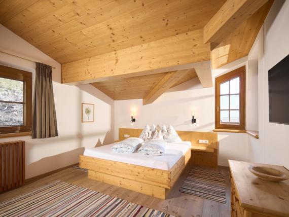 Hochfeldhof Schlafzimmer mit Holzdecke, Doppelbett und zwei Fenstern