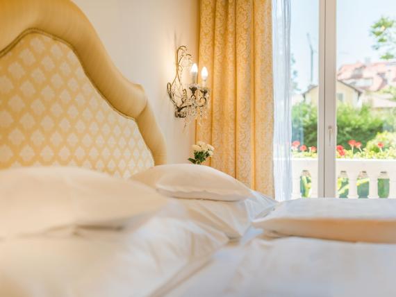 Bright and cozy Hotel Adria room with canopy bed and balcony view