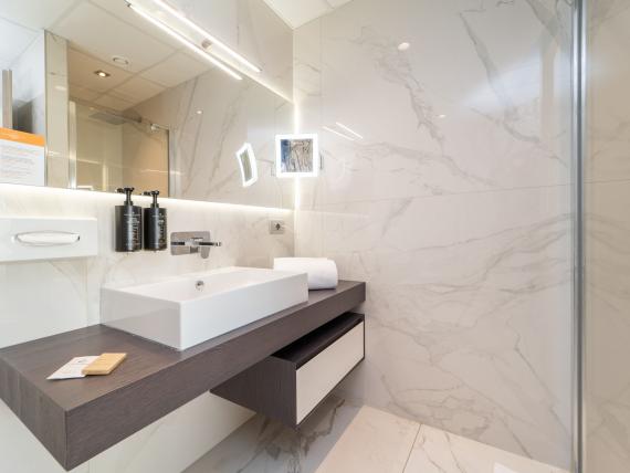 Bagno moderno al Bibione Palace Hotel con lavabo e specchio illuminato