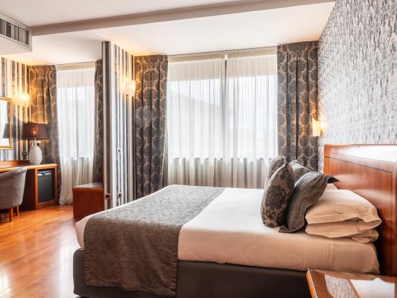 Camera luminosa con letto e carta da parati decorativa al Montresor Hotel Palace Verona