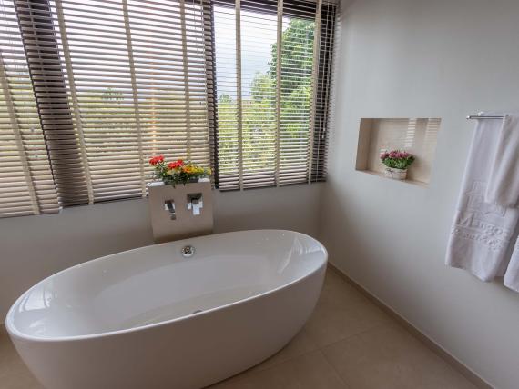 Modern bathtub beside large windows at The Mangosteen Ayurveda & Wellness Resort bathroom
