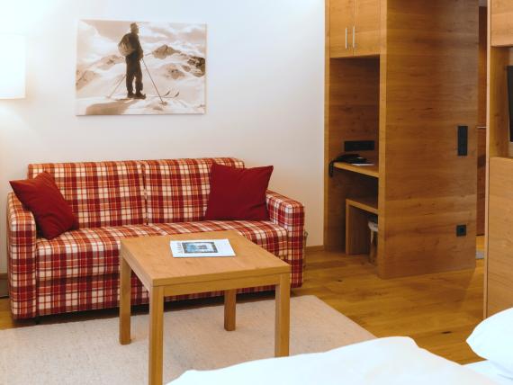 Hotel Panorama Lounge mit kariertem Sofa, Holzeinbauten und Fernseher