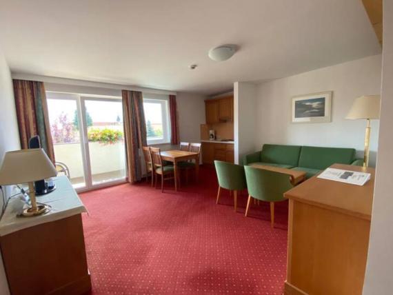 Hotel Moarhof Zimmer mit grünem Sofa, Essbereich und Balkon