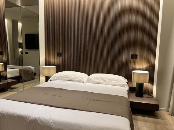 Camera da letto con letto matrimoniale e lampade in Evangelisti Palace Suite & Apartments