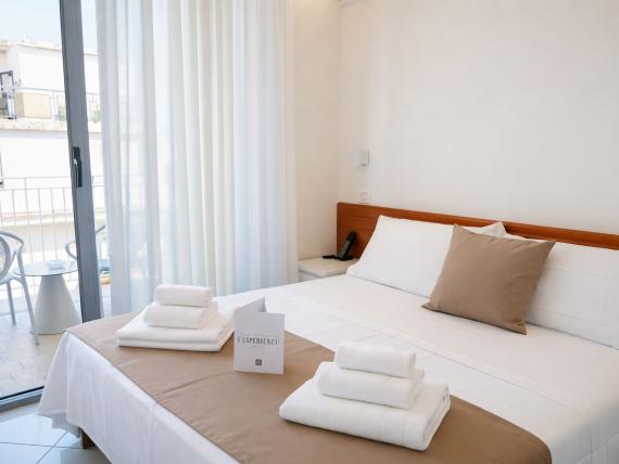 Camera accogliente al Regal Hotel Rimini con balcone e asciugamani bianchi