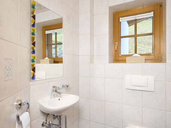 Helles Badezimmer mit Wandtoilette und Waschbecken im Hochfeldhof