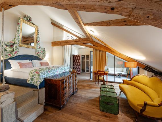 Gemütliches Schlafzimmer mit Holzbalken und gelbem Sofa in Castel Sallegg