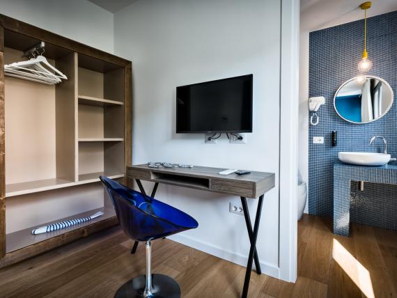 Camera del Teku Boutique Hotel con scrivania, sedia blu, TV e lavabo a vista