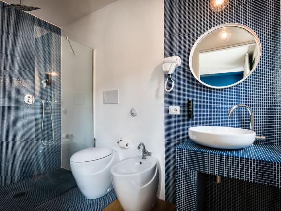 Bagno del Teku Boutique Hotel con mosaico blu e specchio rotondo