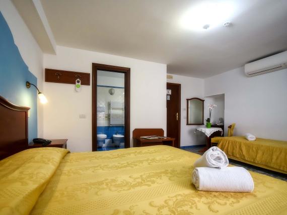 Camera dell'Hotel Amalfi con letti gialli, bagno e arredamento semplice