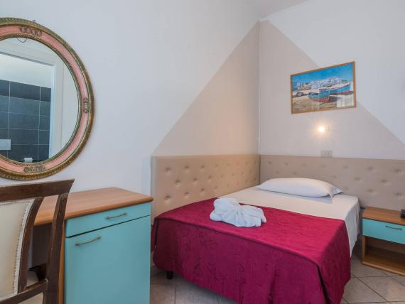 Piccola camera con copriletto rosso e fiori fatti con asciugamani